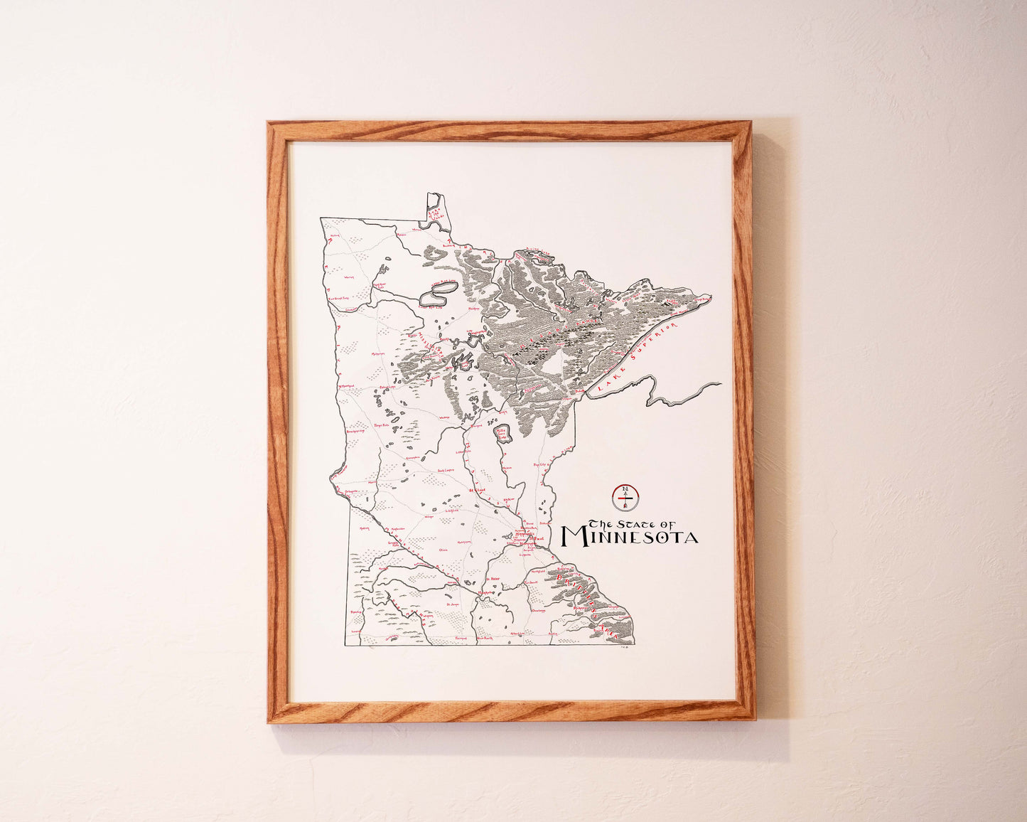 A framed map of Minnesota hangs on a light-colored wall, featuring detailed markings and the text “The State of Minnesota” at the bottom right.