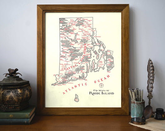 The Rhode Island Map by Lord of Maps, a vintage-style framed wall art labeled with regions, sits on a desk with books, art supplies, and decor. “Atlantic Ocean” and “The State of Rhode Island” appear on the map.