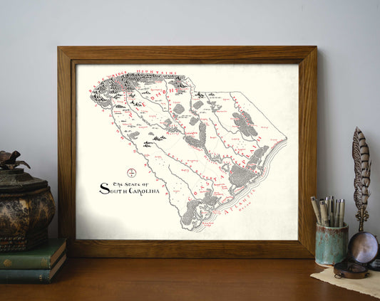 The South Carolina Map by Lord of Maps is a framed hand-drawn print featuring detailed black and red landmark illustrations, perfect for displaying on your desk alongside books and pens.